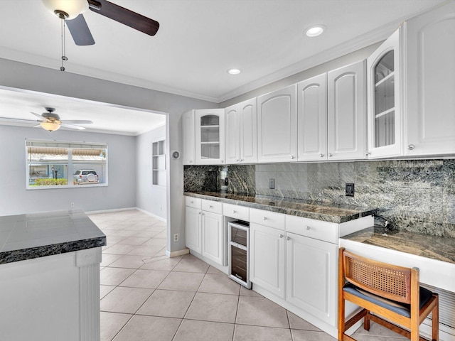 kitchen with backsplash, glass insert cabinets, crown molding, and ceiling fan