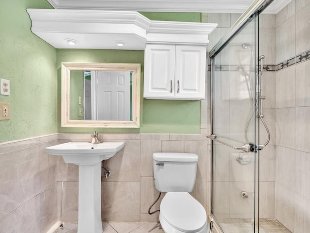 bathroom with a shower stall, toilet, wainscoting, and tile walls