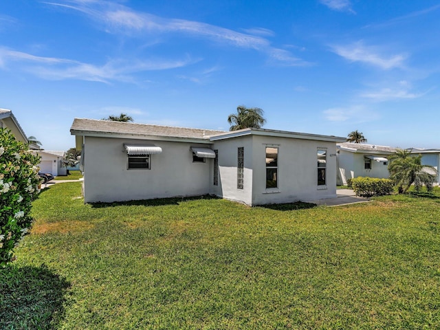 back of property with a lawn and stucco siding
