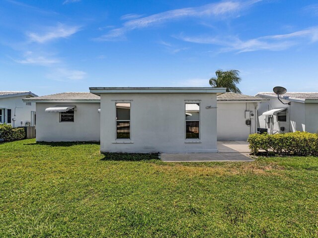 rear view of property with a lawn, a patio, and stucco siding