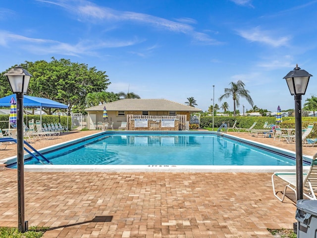 community pool with a patio area and fence