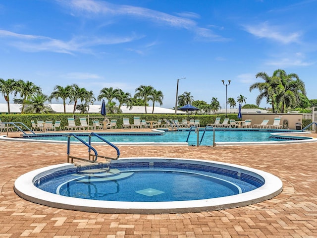 community pool with a hot tub and a patio