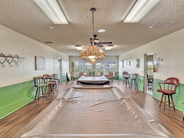 dining area featuring ceiling fan, wood finished floors, visible vents, and a textured ceiling