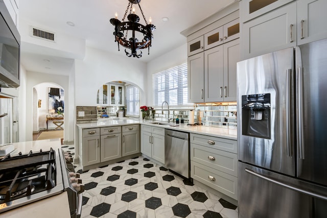 359 E Lakewood Rd, West Palm Beach, FL 33405 - kitchen with stainless steel appliances, a sink, arched walkways, a notable chandelier, and gray cabinets