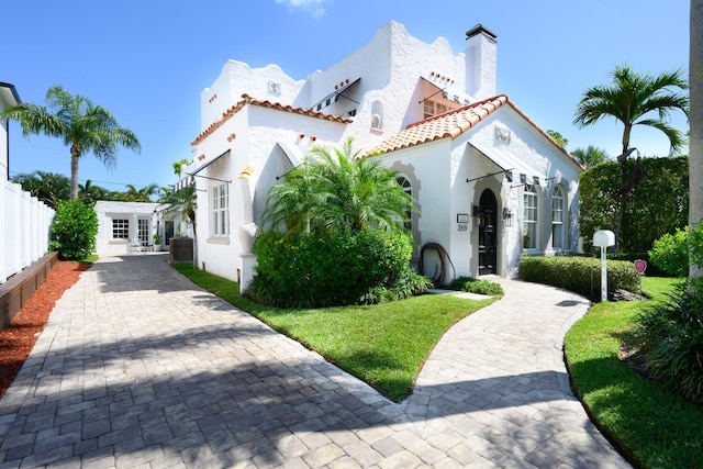 359 E Lakewood Rd, West Palm Beach, FL 33405 - mediterranean / spanish-style home featuring a tiled roof, fence, central AC, and stucco siding