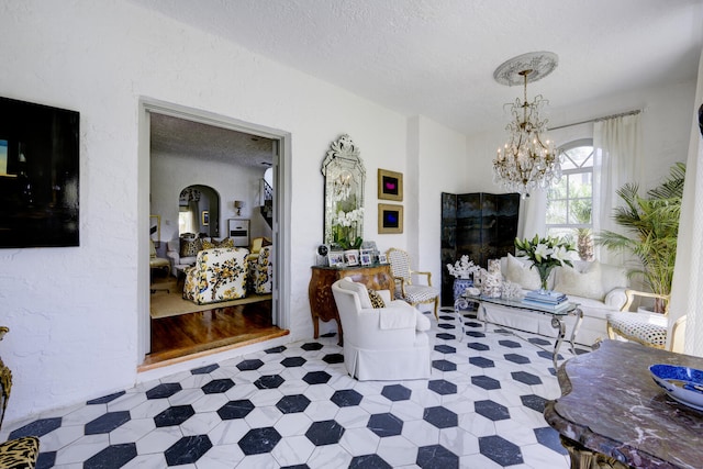 359 E Lakewood Rd, West Palm Beach, FL 33405 - living area featuring tile patterned floors, arched walkways, a textured ceiling, and a notable chandelier