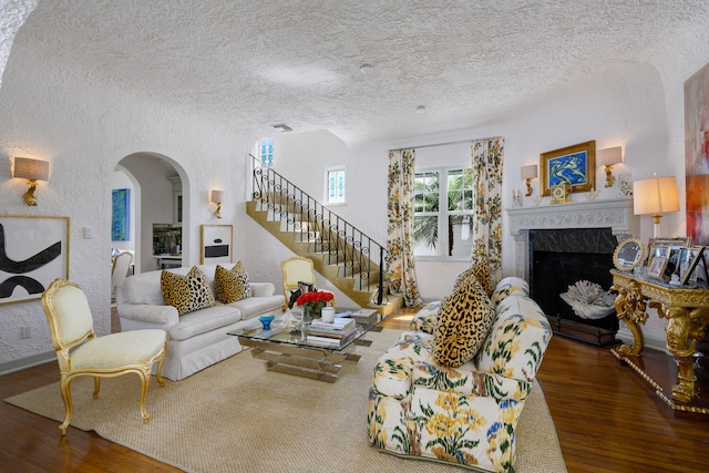 359 E Lakewood Rd, West Palm Beach, FL 33405 - living area featuring arched walkways, a textured wall, a textured ceiling, a high end fireplace, and wood finished floors