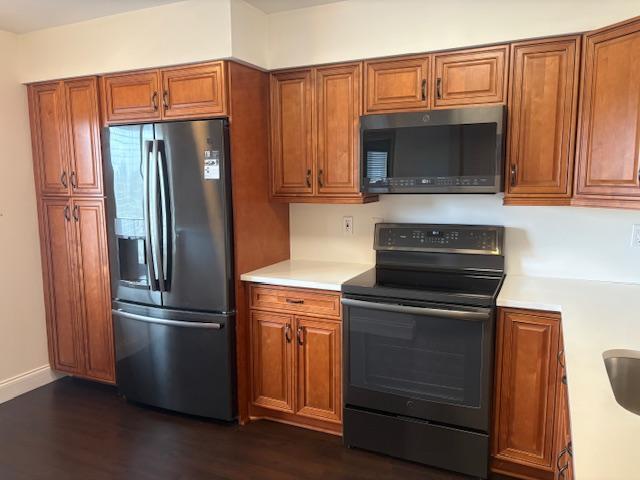 7290 Kinghurst Dr Unit 407, Delray Beach, FL 33446 - kitchen featuring stainless steel appliances, brown cabinets, light countertops, and dark wood-style flooring
