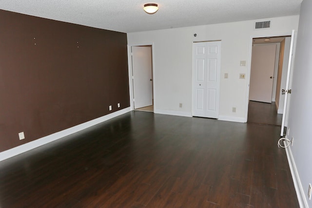 unfurnished room featuring a textured ceiling, baseboards, visible vents, and wood finished floors