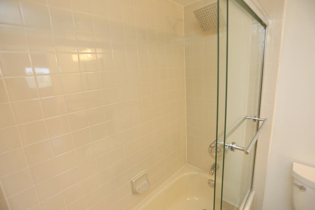 bathroom with bath / shower combo with glass door and toilet