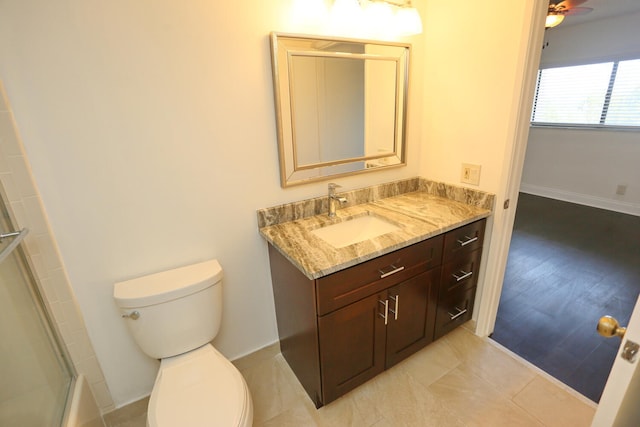 bathroom featuring toilet, baseboards, a shower with shower door, and vanity