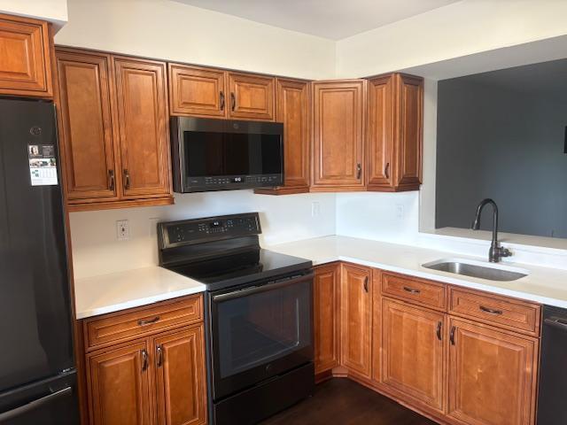 7290 Kinghurst Dr Unit 407, Delray Beach, FL 33446 - kitchen with black appliances, a sink, and brown cabinets