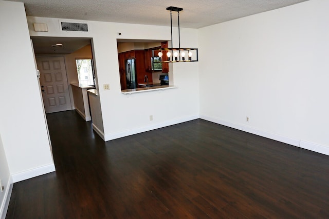 unfurnished dining area featuring visible vents, a textured ceiling, dark wood finished floors, and baseboards