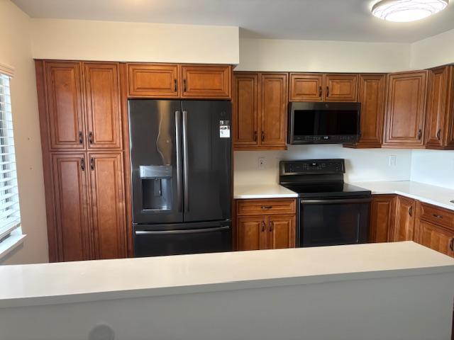 7290 Kinghurst Dr Unit 407, Delray Beach, FL 33446 - kitchen featuring black appliances, brown cabinetry, and healthy amount of natural light