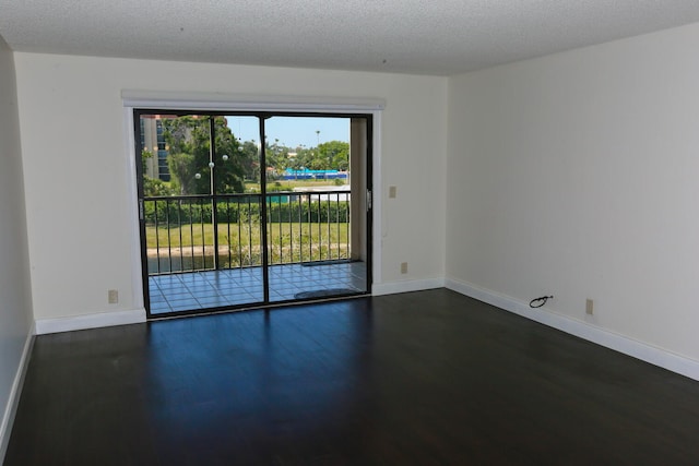 empty room with baseboards, a textured ceiling, and wood finished floors