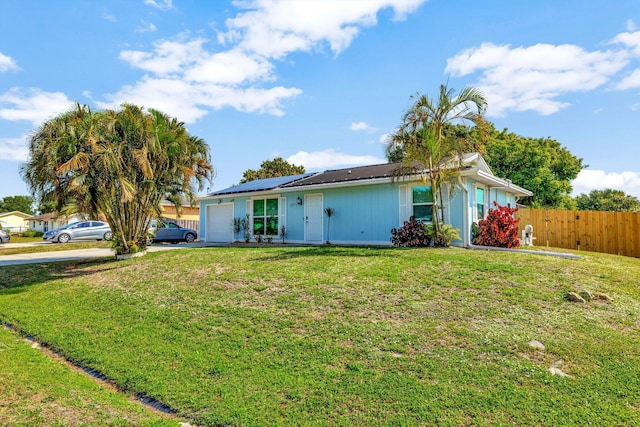 ranch-style home featuring a front yard, metal roof, a garage, fence, and driveway