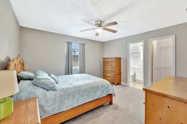 bedroom with light carpet, ensuite bath, a ceiling fan, and a textured ceiling