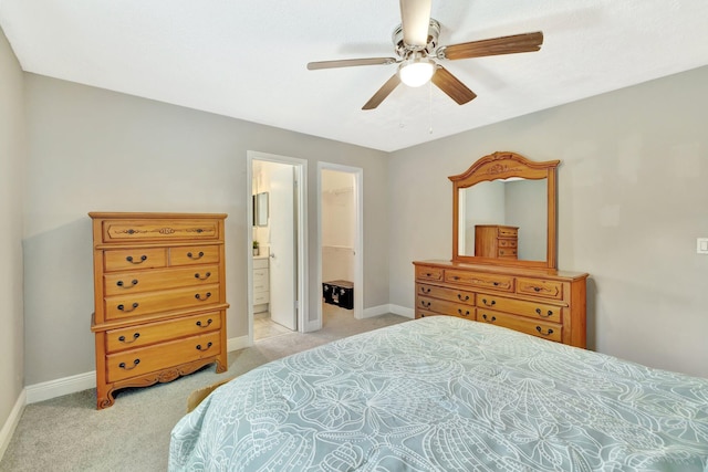 bedroom featuring a walk in closet, light colored carpet, and baseboards