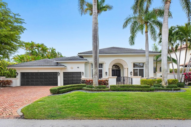 view of front facade featuring stucco siding, a front lawn, decorative driveway, and a garage