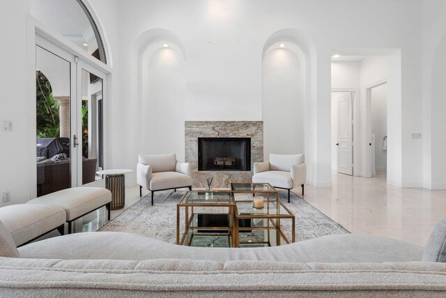 living area featuring arched walkways, baseboards, french doors, and a premium fireplace