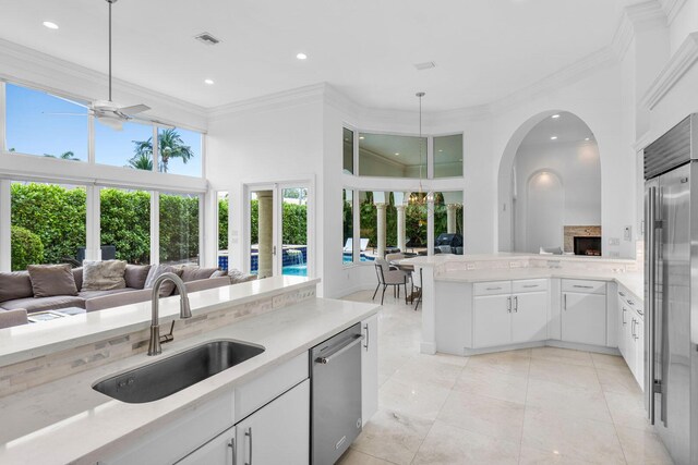 kitchen featuring a ceiling fan, a sink, hanging light fixtures, open floor plan, and stainless steel appliances
