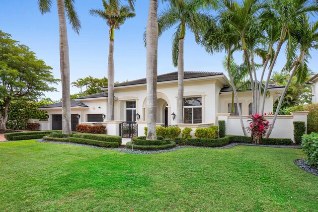view of front facade with fence private yard, an attached garage, a front lawn, and stucco siding