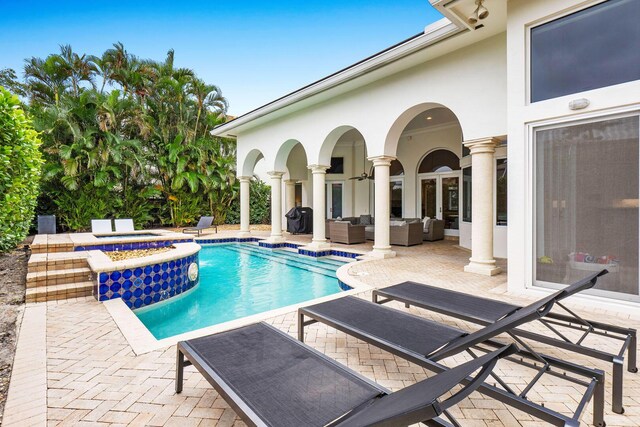outdoor pool featuring an in ground hot tub, a patio area, and an outdoor hangout area