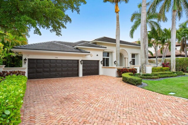 view of front of home featuring a garage, a tile roof, stucco siding, and decorative driveway