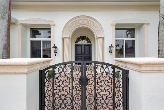 entrance to property featuring a gate and stucco siding