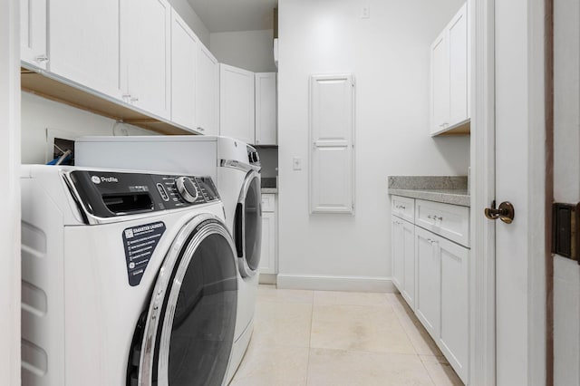washroom featuring cabinet space, washing machine and dryer, baseboards, and light tile patterned floors