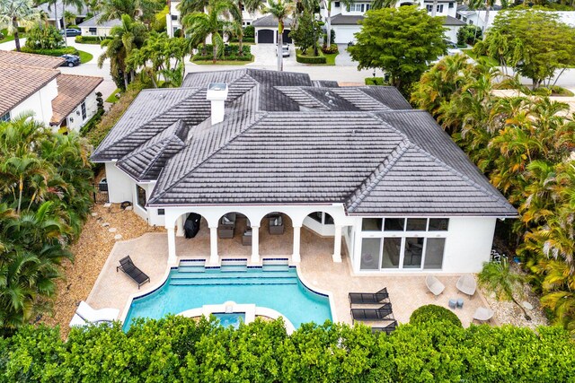 back of house with a tile roof, a patio, an outdoor pool, and stucco siding