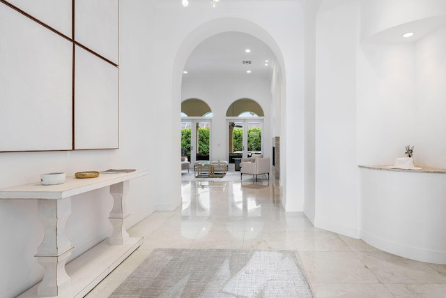hall featuring marble finish floor, arched walkways, baseboards, and recessed lighting