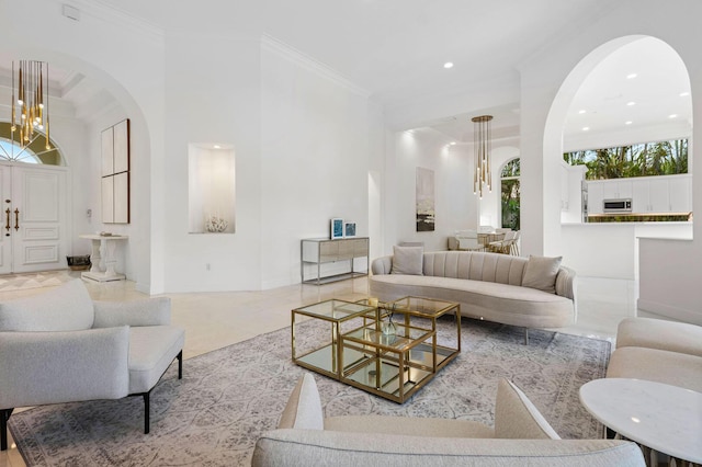 living area featuring arched walkways, an inviting chandelier, ornamental molding, and recessed lighting