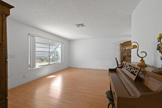 empty room featuring a textured ceiling, visible vents, and wood finished floors