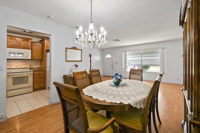 dining area with visible vents, an inviting chandelier, light wood-type flooring, and a textured ceiling