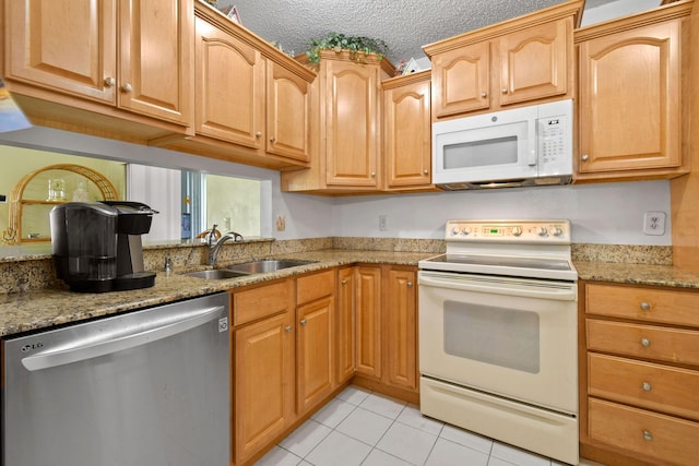 kitchen with a sink, white appliances, a textured ceiling, light stone counters, and light tile patterned floors