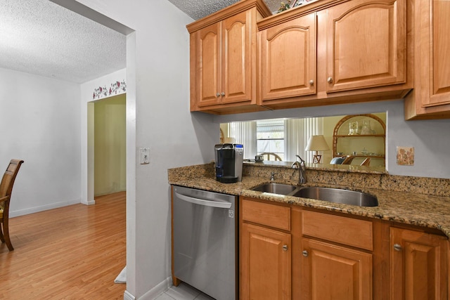 kitchen with a sink, stone counters, a textured ceiling, and dishwasher