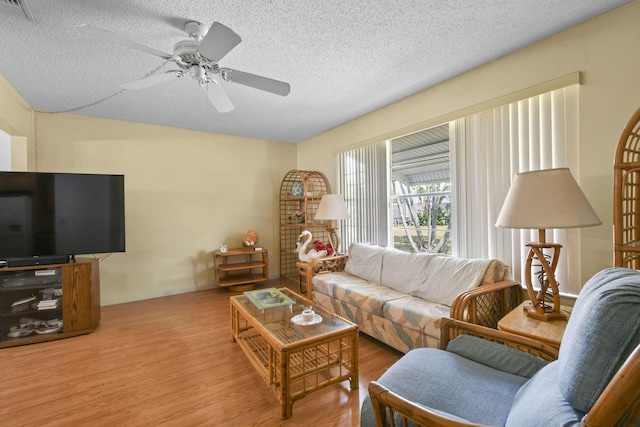 living area featuring a ceiling fan, visible vents, a textured ceiling, and wood finished floors