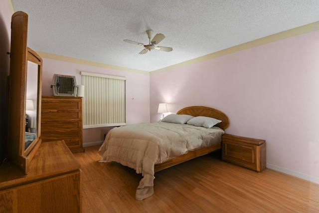 bedroom with a ceiling fan, a textured ceiling, wood finished floors, and baseboards