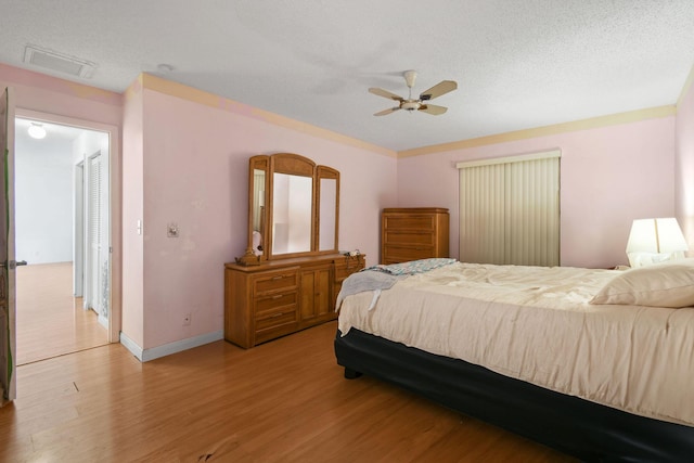 bedroom featuring a textured ceiling, baseboards, light wood-type flooring, and visible vents
