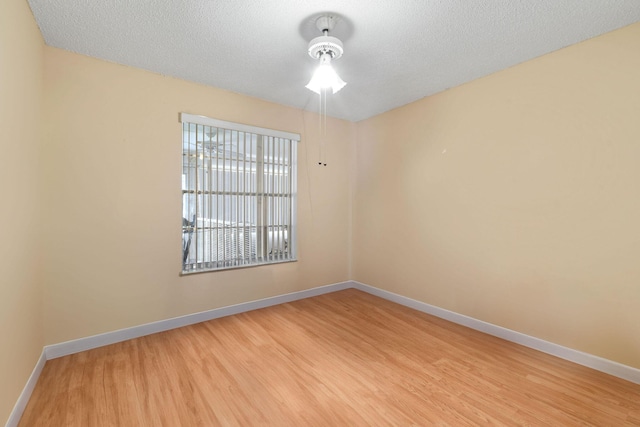 spare room featuring a textured ceiling, baseboards, and wood finished floors