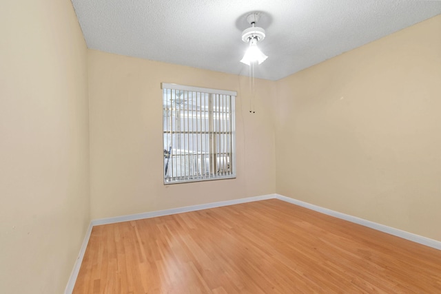 unfurnished room featuring baseboards, a textured ceiling, and wood finished floors