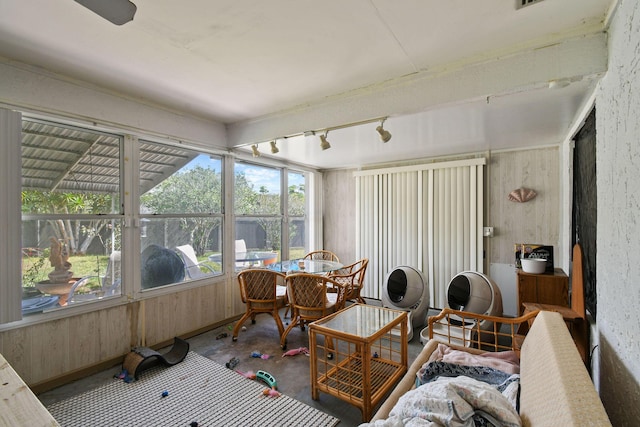 sunroom / solarium featuring track lighting and concrete floors