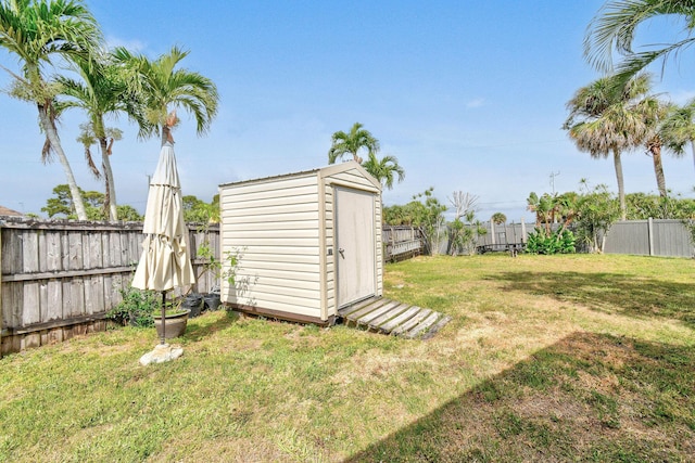 view of yard featuring an outbuilding, a fenced backyard, and a storage unit