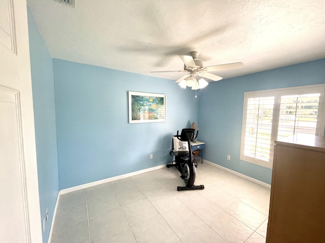 unfurnished office with a textured ceiling, light tile patterned flooring, baseboards, and a ceiling fan