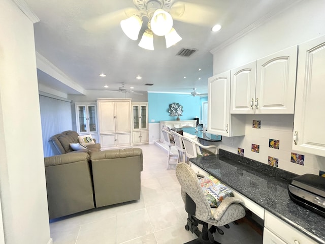 living area with crown molding, light tile patterned floors, a ceiling fan, visible vents, and built in study area
