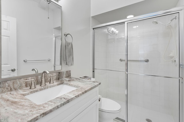 bathroom with a shower stall, vanity, and toilet