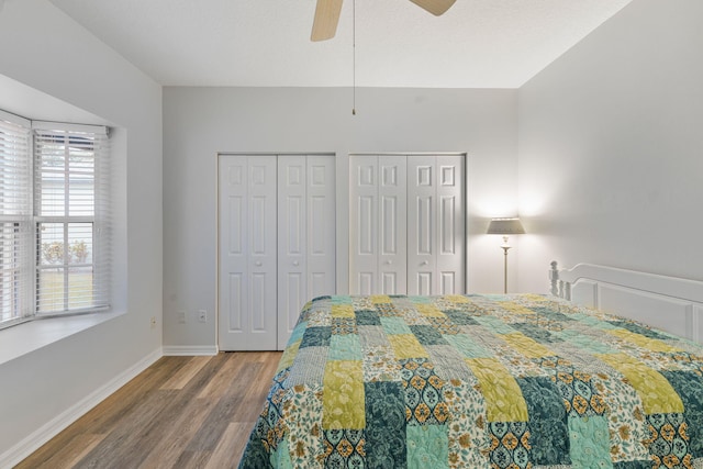 bedroom featuring ceiling fan, baseboards, multiple closets, and wood finished floors