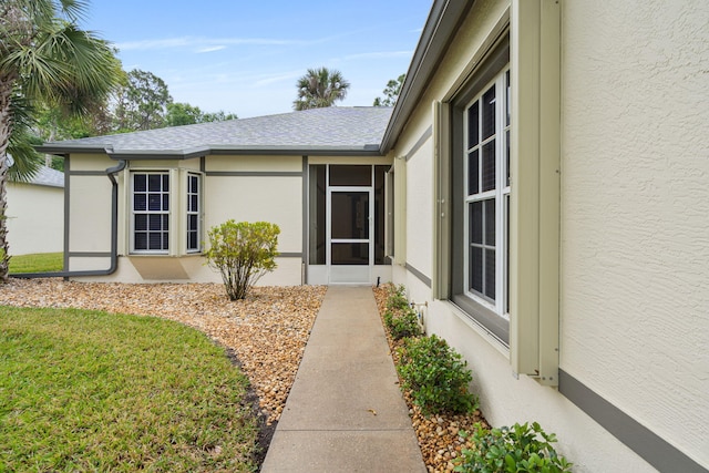 entrance to property with roof with shingles and stucco siding