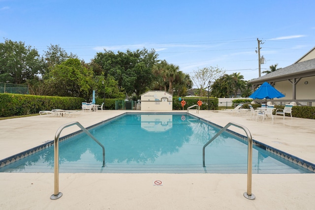 pool with a patio and fence